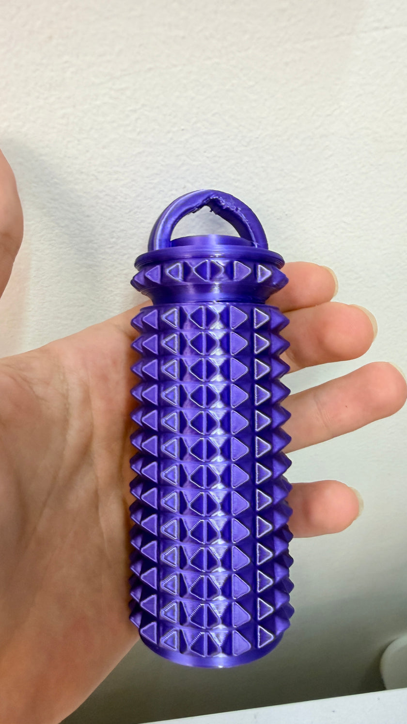 Hand holding purple spiky massager with storage lid for crochet and knitting hand care