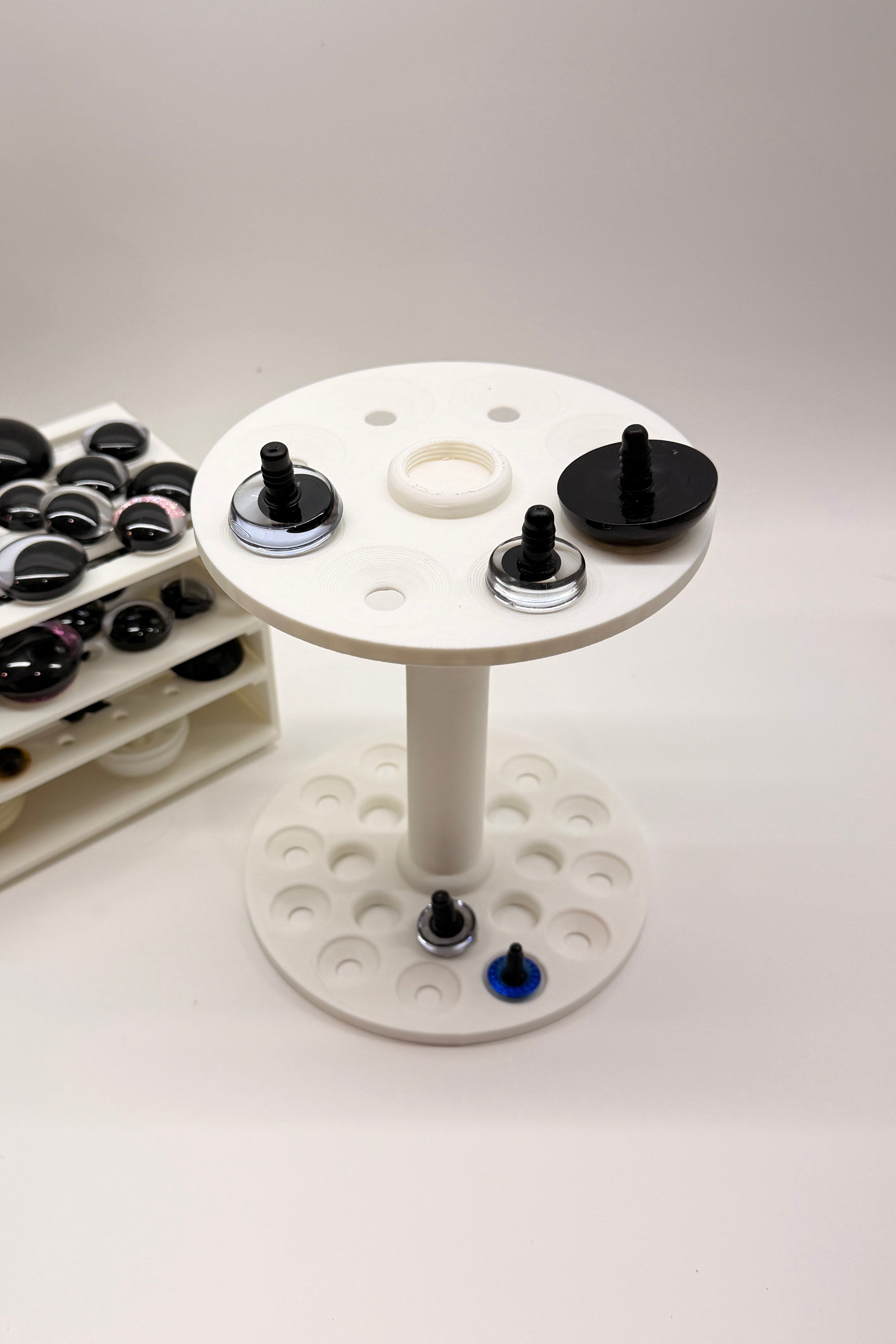 Close-up of the Safety Eye Painter holding standard and sinker safety eyes, designed for painting, drying, and organizing amigurumi eyes.