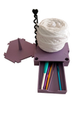 Build-A-Spin modular yarn spinner with purple base, white yarn ball, and sliding crochet hook storage drawer on transparent background